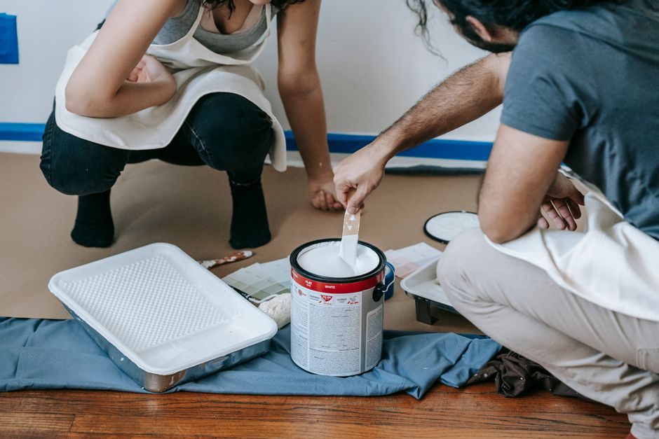 A couple paints their new home together, preparing walls for a fresh look.